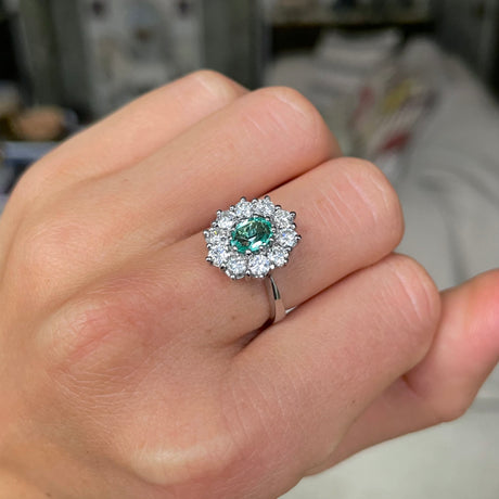 Austrian emerald and diamond cluster engagement ring, worn on hand.