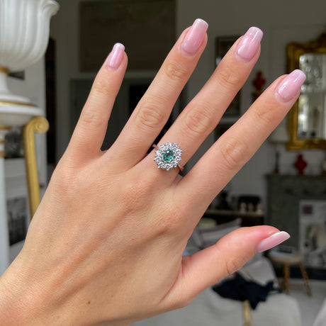 Austrian emerald and diamond cluster engagement ring, worn on hand.