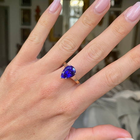 Blue tanzanite single stone ring, worn on hand.