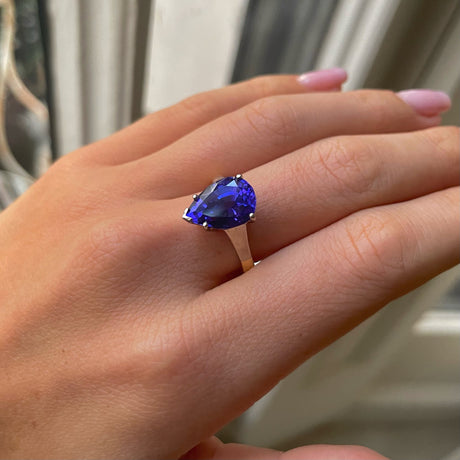 Blue tanzanite single stone ring, worn on hand.