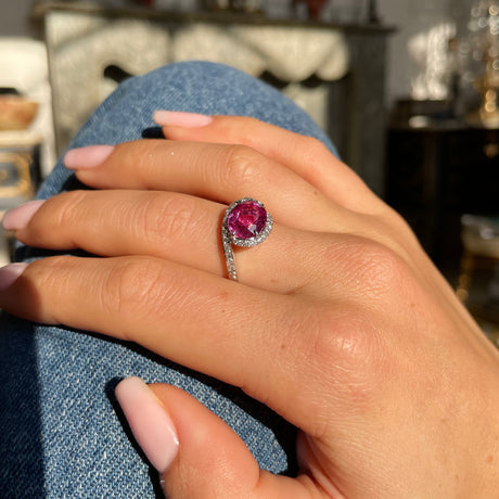 Pink sapphire and diamond engagement ring, worn on hand.