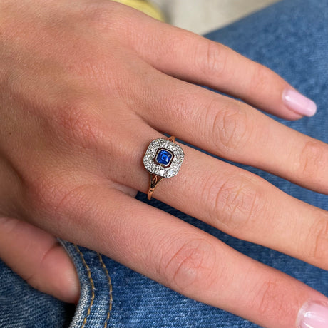 Sapphire and diamond engagement ring, worn on hand.