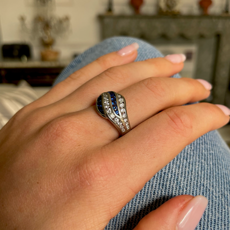 An unusual sapphire and diamond wave ring, worn on hand.