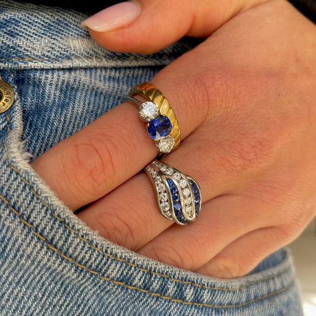 An unusual sapphire and diamond wave ring, worn on hand.