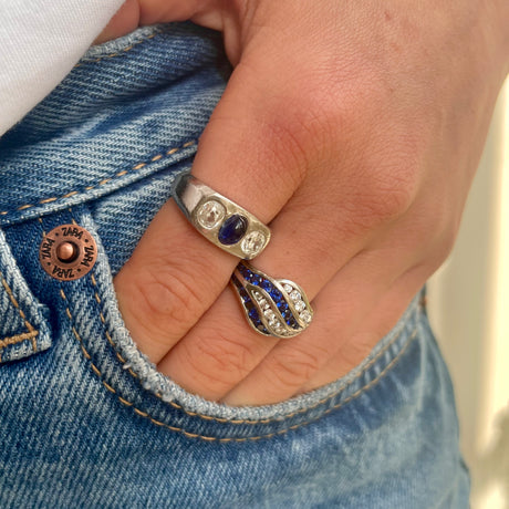 An unusual sapphire and diamond wave ring worn on hand placed in pocket of jeans.