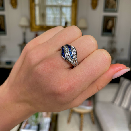 An unusual sapphire and diamond wave ring, worn on hand.