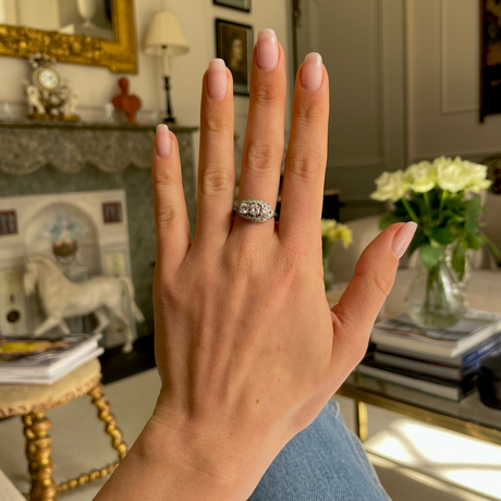 Art Deco three-stone diamond engagement ring, worn on hand.