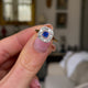 Sapphire and diamond engagement ring, held in fingers and rotated to give perspective.
