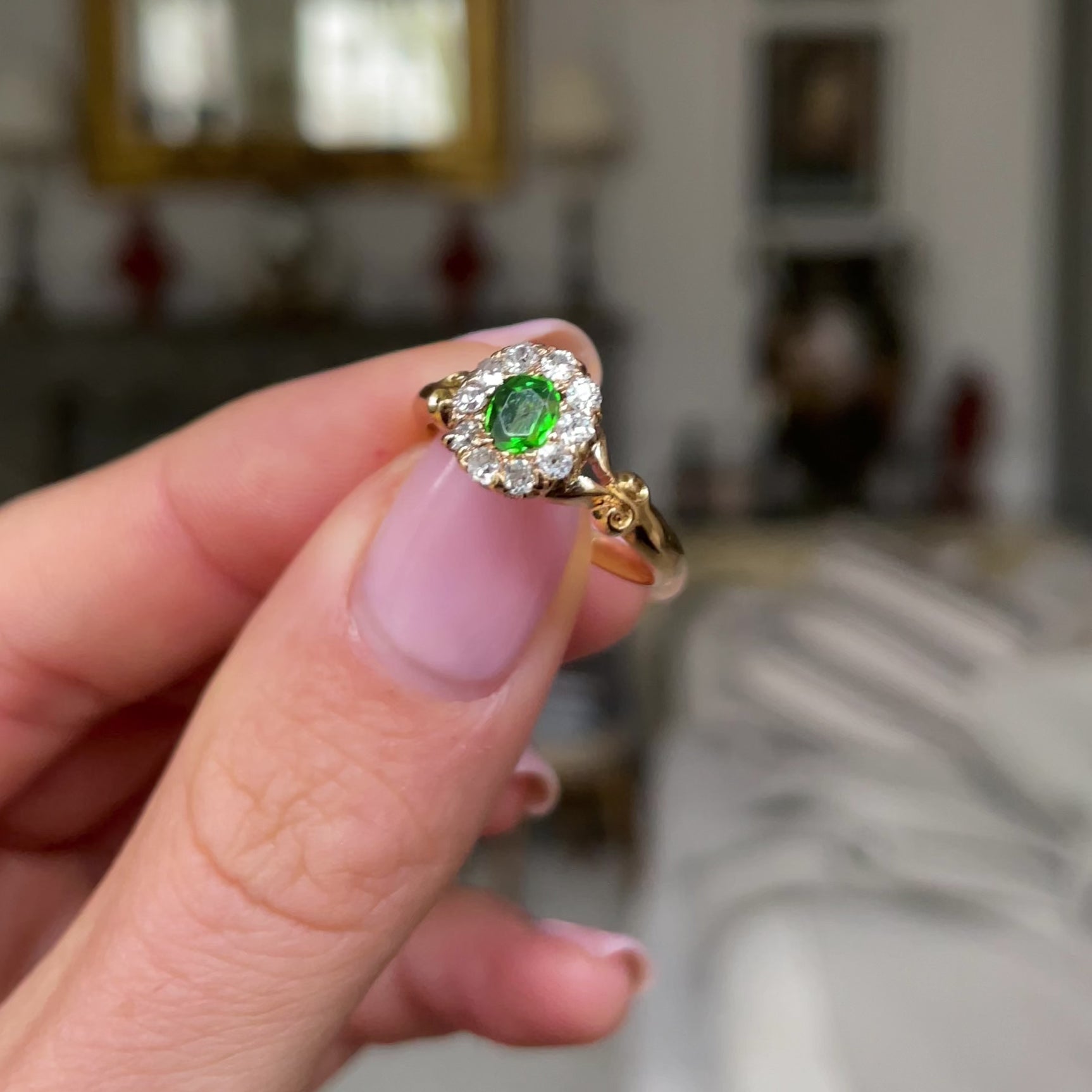 Edwardian, demantoid garnet and diamond cluster ring, held in fingers and rotated to give perspective.